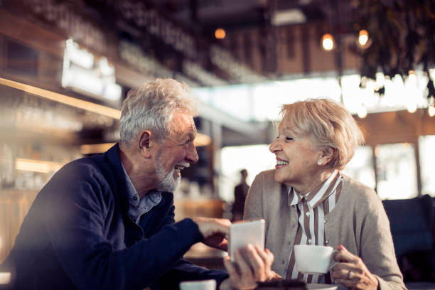 Close up of a happy seniors couple using a phone in a cafe