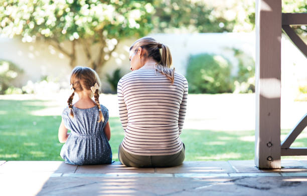 Rea rview shot of a young woman and her daughter having a conversation on the porch